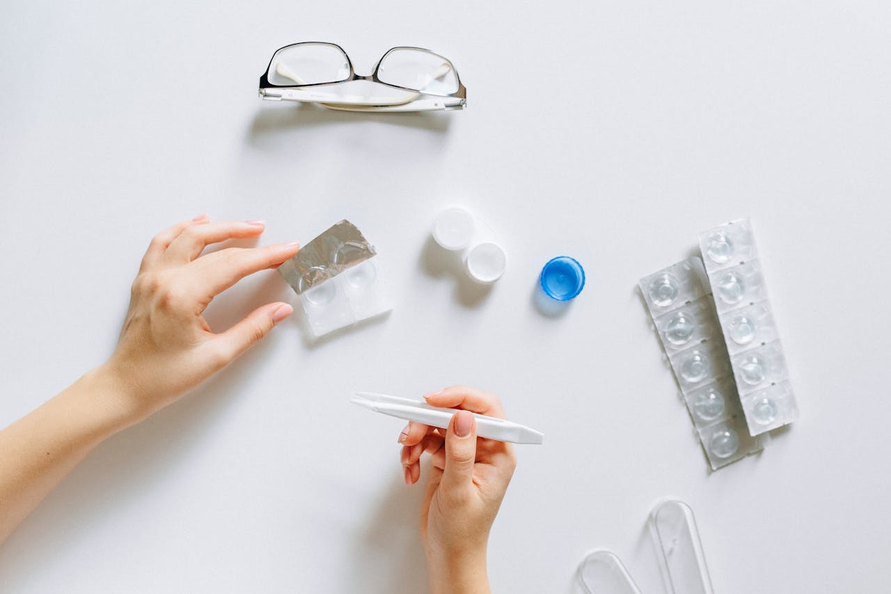 Flat lay setup of contact lenses with eyeglasses for eye care on a white background.